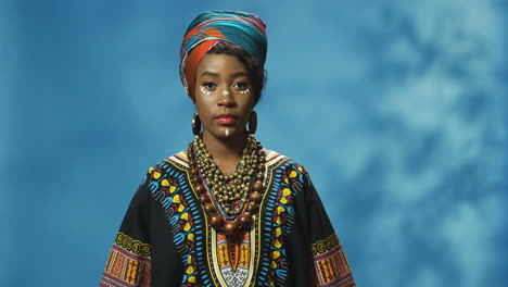 African-American-young-woman-in-turban-and-make-up-looking-with-serious-expression-at-camera