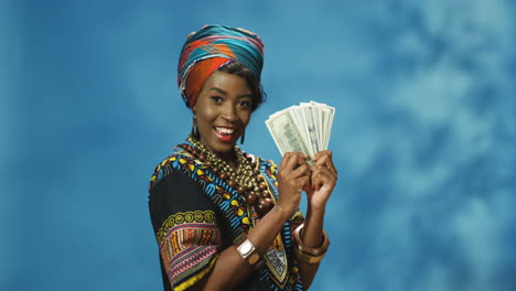 Afroamerikanische-Junge-Frau-In-Turban-Und-Traditioneller-Kleidung,-Die-Geld-Hält-Und-In-Die-Kamera-Schaut