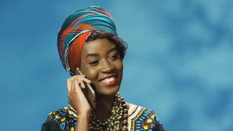 Close-up-view-of-African-American-young-woman-in-turban-and-traditional-clothes-talking-on-the-phone