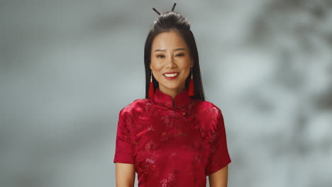 Porträtaufnahme-Einer-Jungen-Fröhlichen-Asiatin-In-Roter-Traditioneller-Kleidung,-Die-In-Die-Kamera-Lächelt