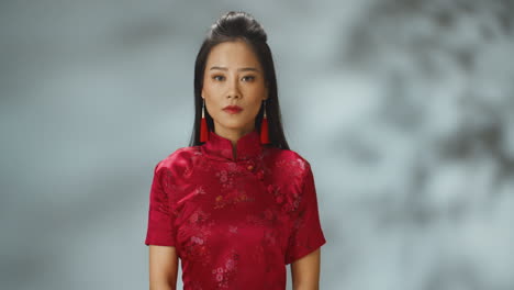 Porträtaufnahme-Einer-Jungen,-Fröhlichen-Asiatin-In-Roter-Traditioneller-Kleidung,-Die-Mit-Ernster-Miene-In-Die-Kamera-Blickt
