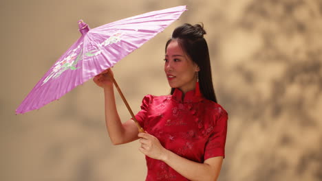 Porträtaufnahme-Einer-Jungen-Fröhlichen-Asiatin-In-Roter-Traditioneller-Kleidung,-Die-Einen-Sonnenschirm-öffnet-Und-In-Die-Kamera-Lächelt