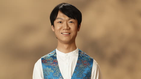 Porträt-Eines-Jungen-Asiatischen-Mannes-In-Traditioneller-Kleidung,-Der-Die-Augen-öffnet-Und-Fröhlich-In-Die-Kamera-Lächelt