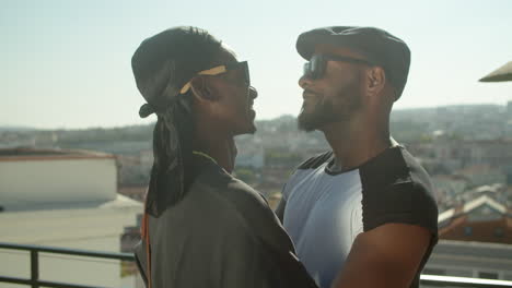 Side-view-of-Afro-American-gays-standing-on-rooftop-and-hugging