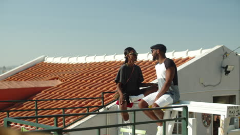Long-shot-of-Afro-American-gays-sitting-on-rooftop-and-talking