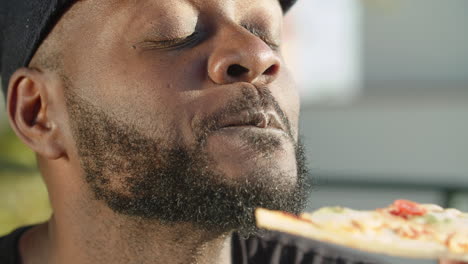 Close-up-shot-of-African-American-gay-eating-delicious-pizza