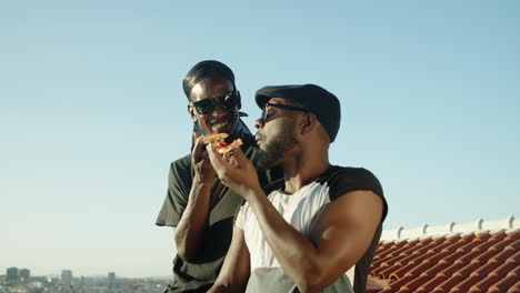 Medium-shot-of-handsome-homosexual-men-eating-pizza-on-rooftop