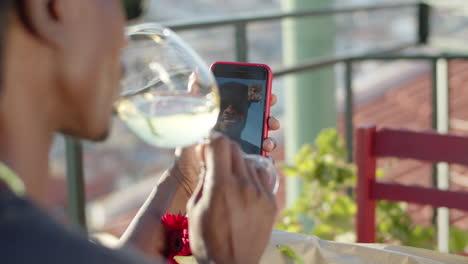 Back-view-of-man-drinking-wine-and-having-video-call-with-lover