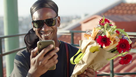 Gay-having-video-call-with-friend-and-showing-flowers-from-lover