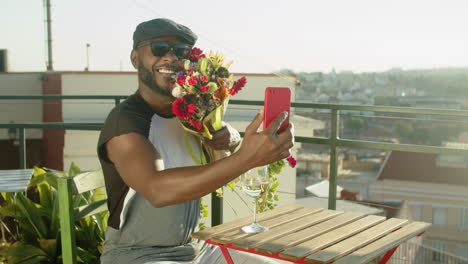 Man-having-video-call-with-boyfriend-while-waiting-him-in-cafe-and-showing-flowers