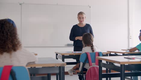 Friendly-female-school-teacher-speaking-at-whiteboard