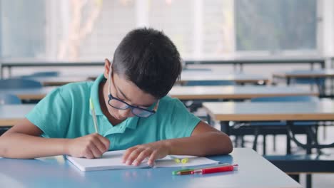 Niño-Alumno-Serio-Y-Trabajador-Con-Gafas-Y-Escribiendo-En-Un-Cuaderno-En-Clase