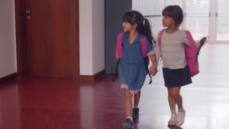 Lindas-Y-Felices-Alumnas-De-La-Escuela-Primaria-Con-Mochilas-Rosas-Y-Caminando-Por-La-Escuela-Cogidas-De-La-Mano