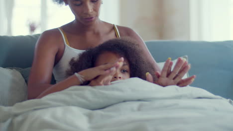 Dolly-shot-of-relaxed-African-American-mum-and-daughter-spending-lazy-weekend-in-bed,-holding-hands