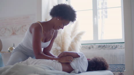 African-American-mother-tickling-her-little-daughter-and-having-fun-together-in-the-bed