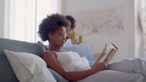 Black-woman-lying-in-bed-reading-when-her-daughter-bringing-tea