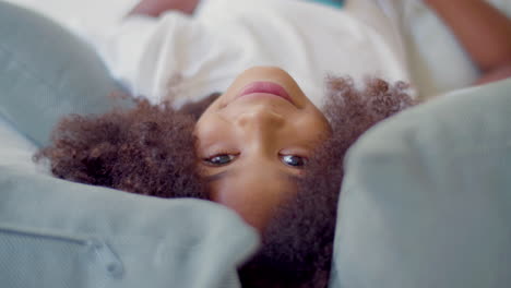 Face-closeup-of-cute-Black-girl-lying-in-bed-and-looking-at-the-camera