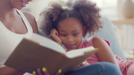 Close-up-of-an-African-American-woman-reading-fairy-tales-to-her-happy-daughter