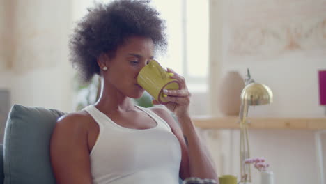 Mittlere-Aufnahme-Einer-Schwarzen-Frau,-Die-Tee-Trinkt,-Während-Sie-Ein-Mobiltelefon-Benutzt