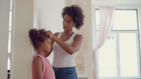 Smiling-Black-woman-measuring-her-daughter's-height-at-the-wall