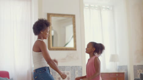 Happy-Black-mum-and-daughter-dancing-at-home-together