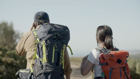 Back-view-of-father-and-daughter-with-backpacks-hiking-together