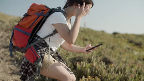 Girl-taking-photo-with-her-phone-while-backpacking-on-a-sunny-day