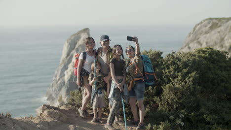 Family-of-backpackers-standing-on-cliff-and-taking-selfie