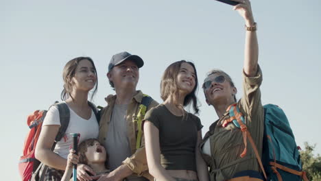Family-of-backpackers-standing-on-cliff-and-taking-selfie