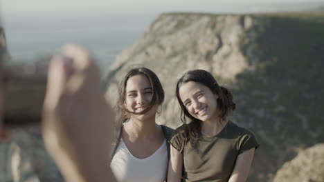 Mother-taking-photo-of-her-daughters-against-mountain-background