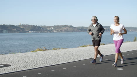 Active-man-and-woman-jogging-on-asphalt-road-along-sea