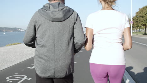 Back-view-of-active-joggers-running-on-asphalt-road