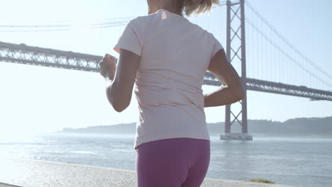 Back-view-of-blonde-woman-running-during-sunny-day