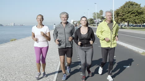 Healthy-group-of-mature-people-jogging-on-road-near-sea