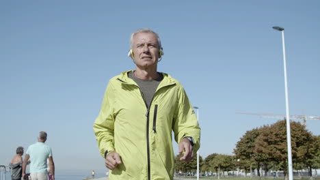 Active-male-pensioner-in-headphones-jogging-outside