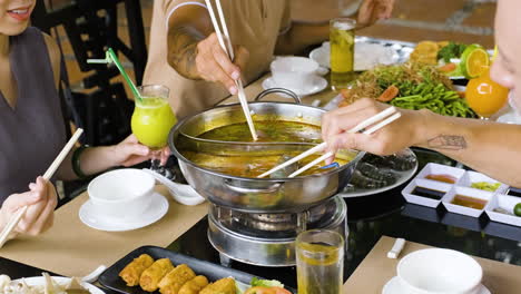 Mitglieder-Einer-Familie,-Die-Im-Chinesischen-Restaurant-Fleisch-Und-Meeresfrüchte-Auf-Hot-Pot-Legen
