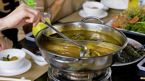 Unrecognizable-person-stirring-vegetables-inside-hot-pot