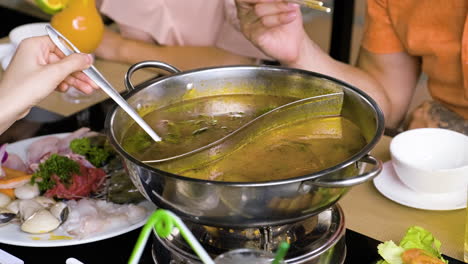 Unrecognizable-person-stirring-hot-pot-at-chinese-restaurant