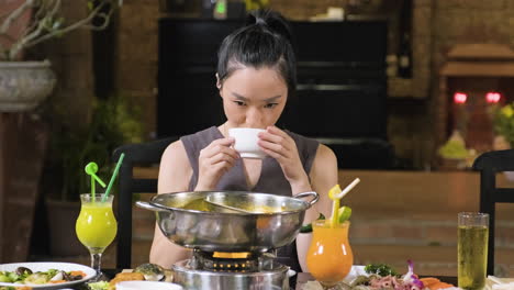 Brunette-woman-drinking-soup-from-white-bowl-in-asian-restaurant