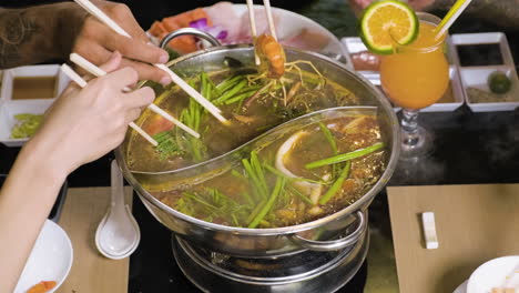 People-eating-from-hot-pot-at-chinese-restaurant