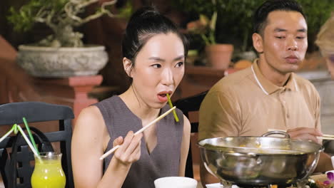 Young-chinese-woman-eating-vegetables-next-to-her-brother-at-the-restaurant