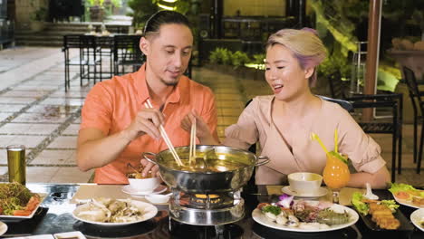 Chinese-couple-talking-and-eating-from-hot-pot
