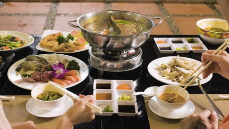 Two-people-taking-food-from-hot-pot