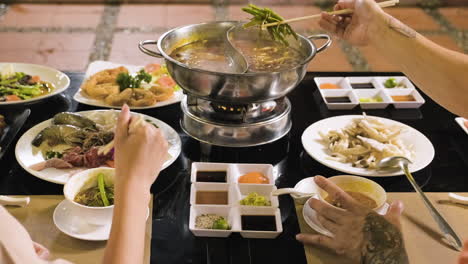 Couple-putting-chinese-food-from-hot-pot-to-white-bowls