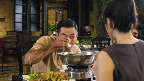 Chinese-guy-eating-and-talking-with-his-date-on-restaurant