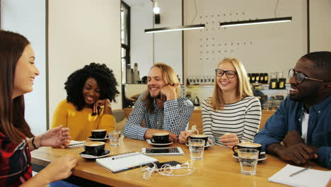 Gruppe-Multiethnische-Gruppe-Von-Freunden,-Die-An-Einem-Tisch-In-Einem-Café-Reden-Und-Lachen