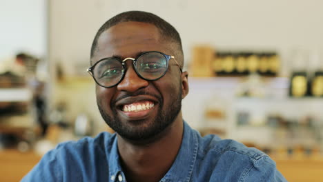 Close-up-view-of-african-american-man-smiling-at-camera-sitting-at-a-table-in-a-cafe