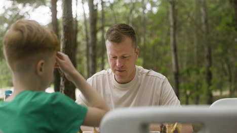 Happy-father-and-son-playing-chess-and-giving-high-five-at-the-camping-in-the-forest