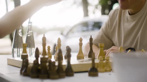 Close-up-of-a-happy-father-and-son-playing-chess-and-giving-high-five-outdoors