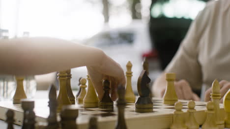 Close-up-of-unrecognizable-father-and-son-playing-chess-outdoors